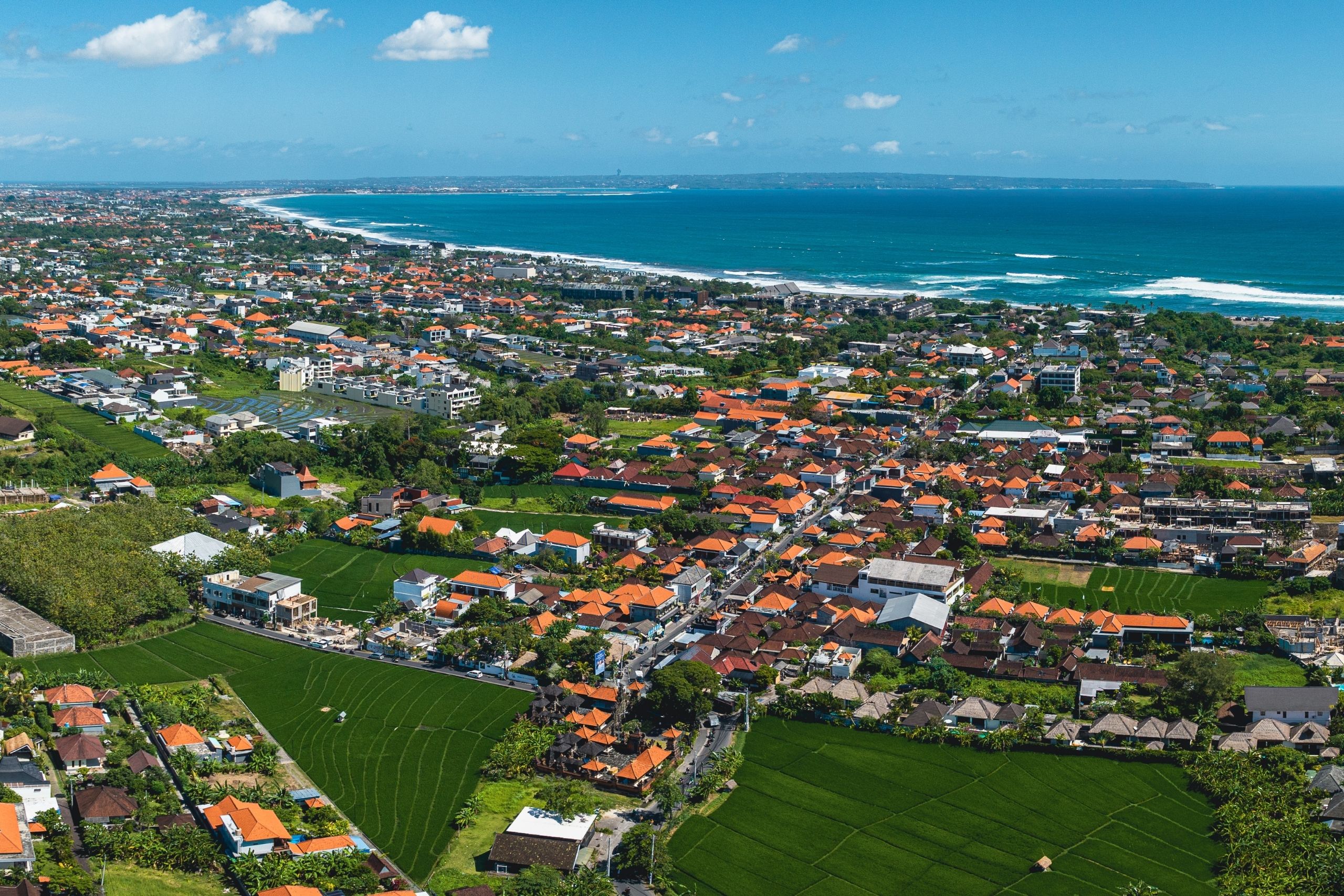Vista panor&aacute;mica de la playa de Canggu al atardecer con surfistas y arena dorada